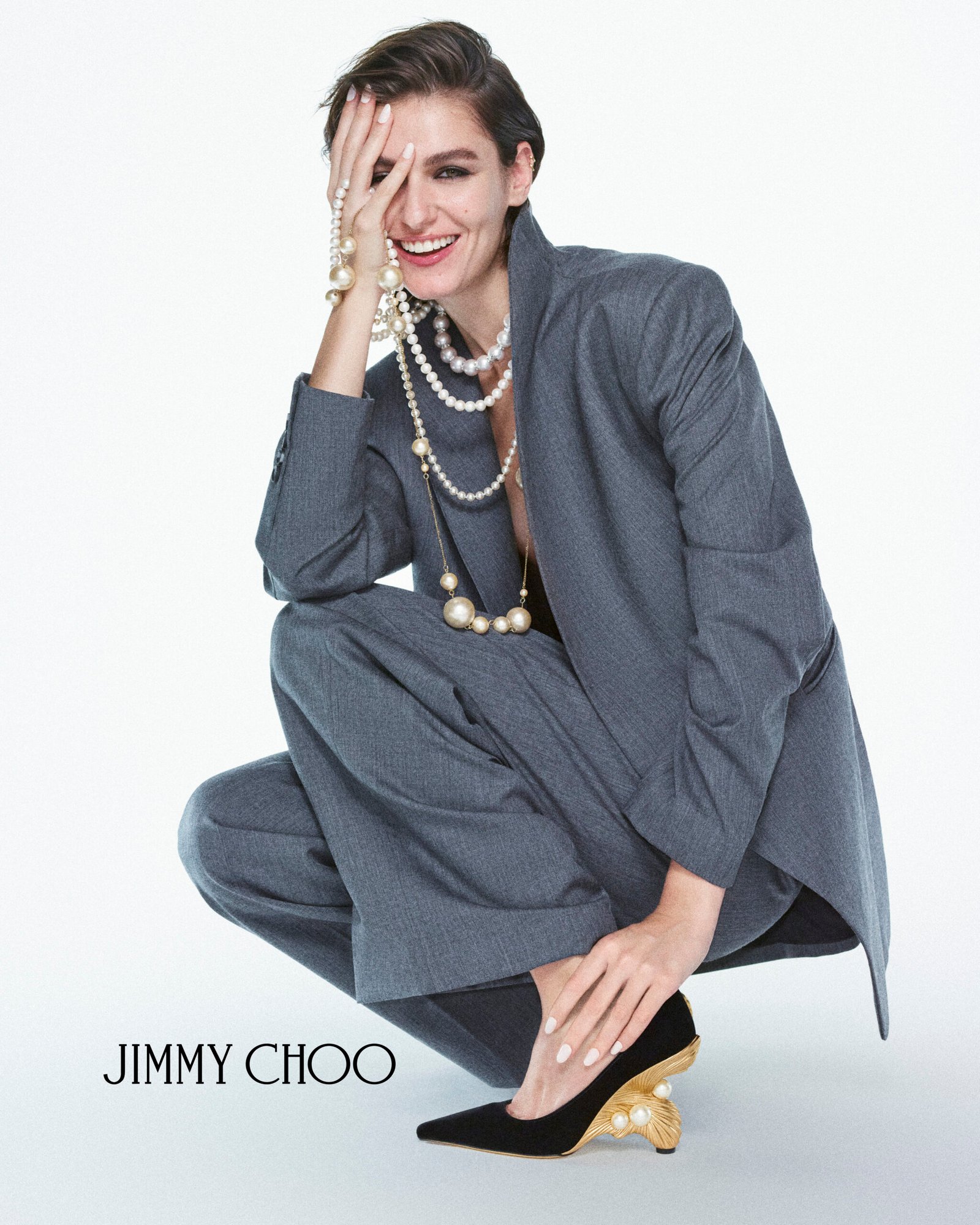 The sculpted gold-tone Ithaca wedge beneath a tailored grey suit