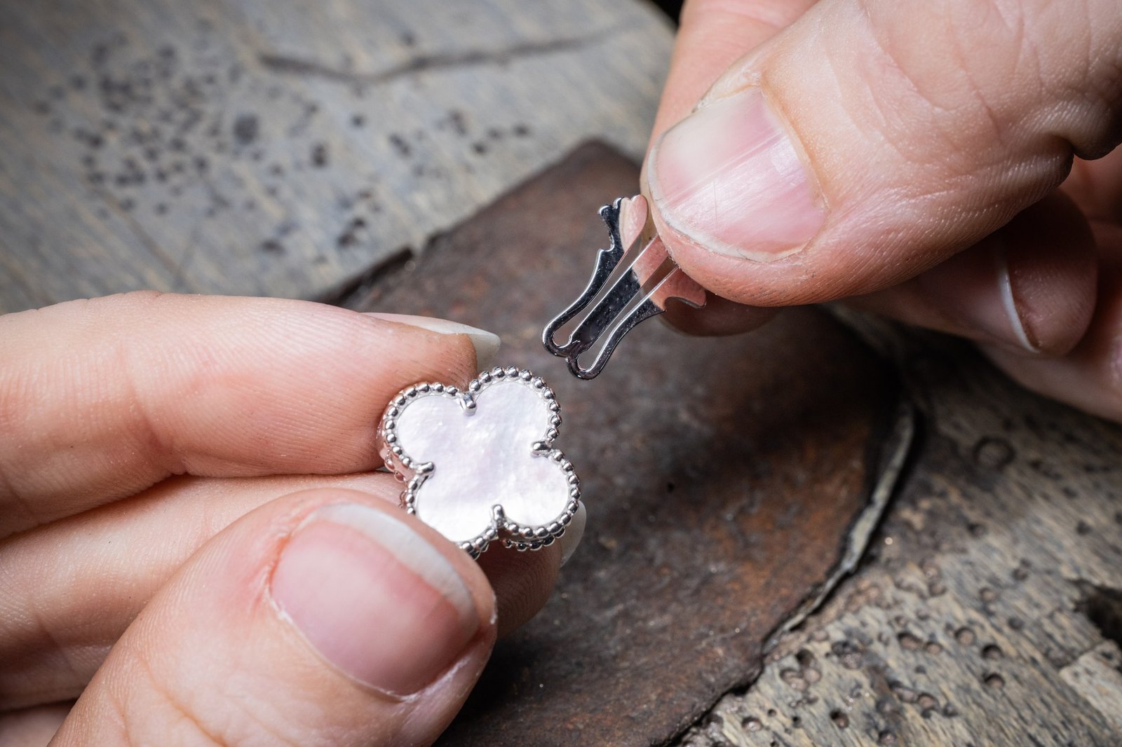 An artisan adjusts a small English blade clasp above an Alhambra motif.