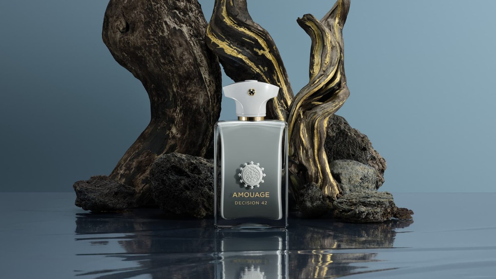 Amouage Decision42 bottle beside gold-accented sculptural wood reflected on a dark surface