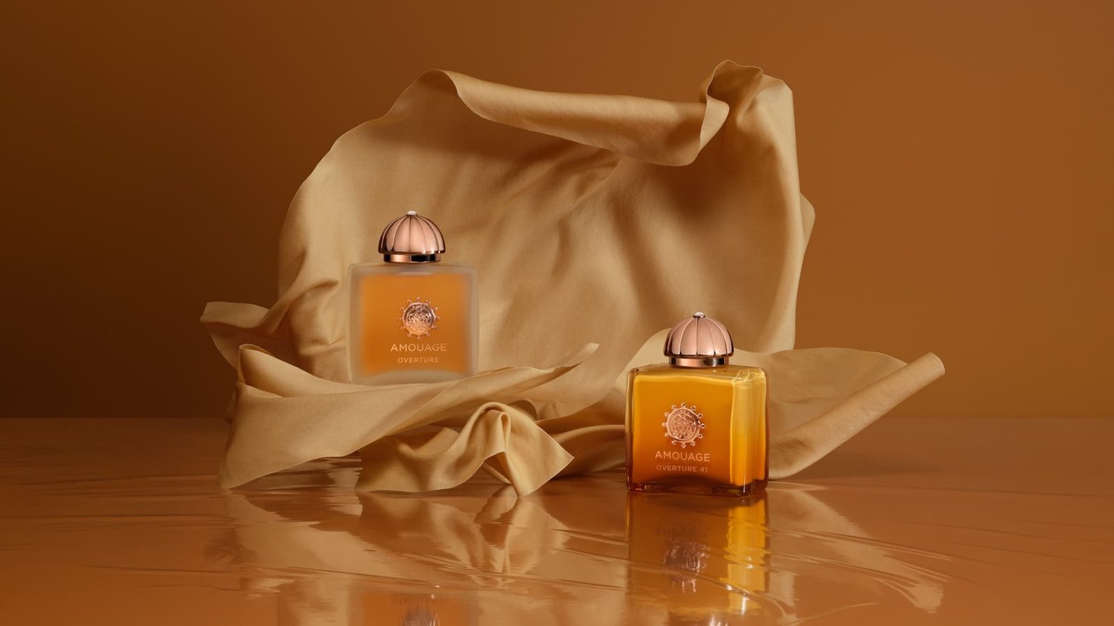 Amouage Overture bottles displayed against folded golden fabric