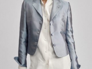 Model wearing a pale blue tailored jacket and matching trousers with an untucked white shirt.