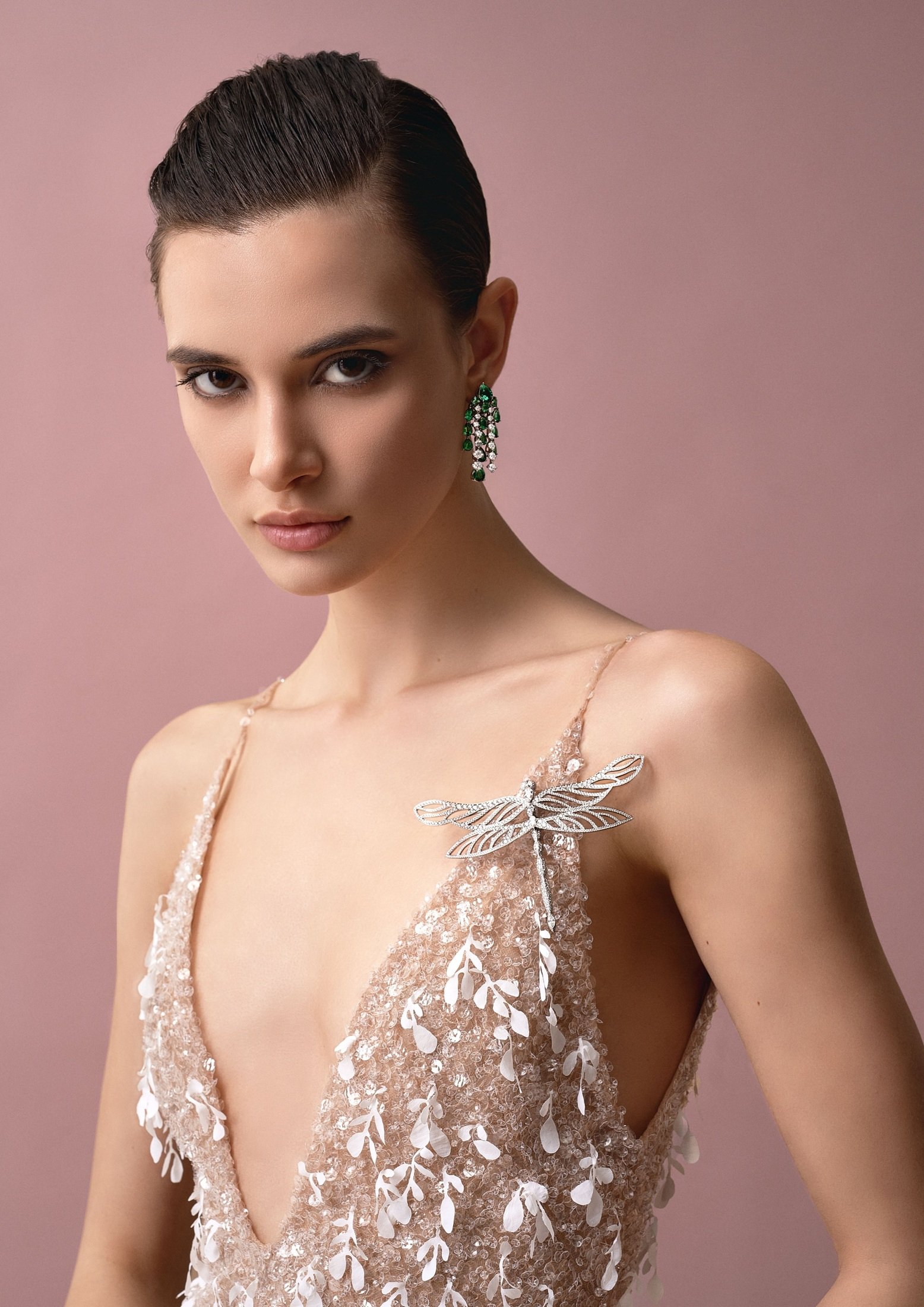 Chopard green earrings and a winged jewel styled with an embroidered evening dress