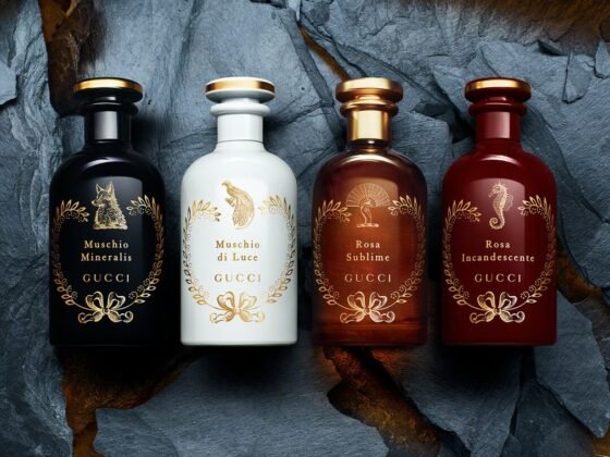 Four black, white, amber and red Gucci fragrance bottles arranged in a fissure in dark stone