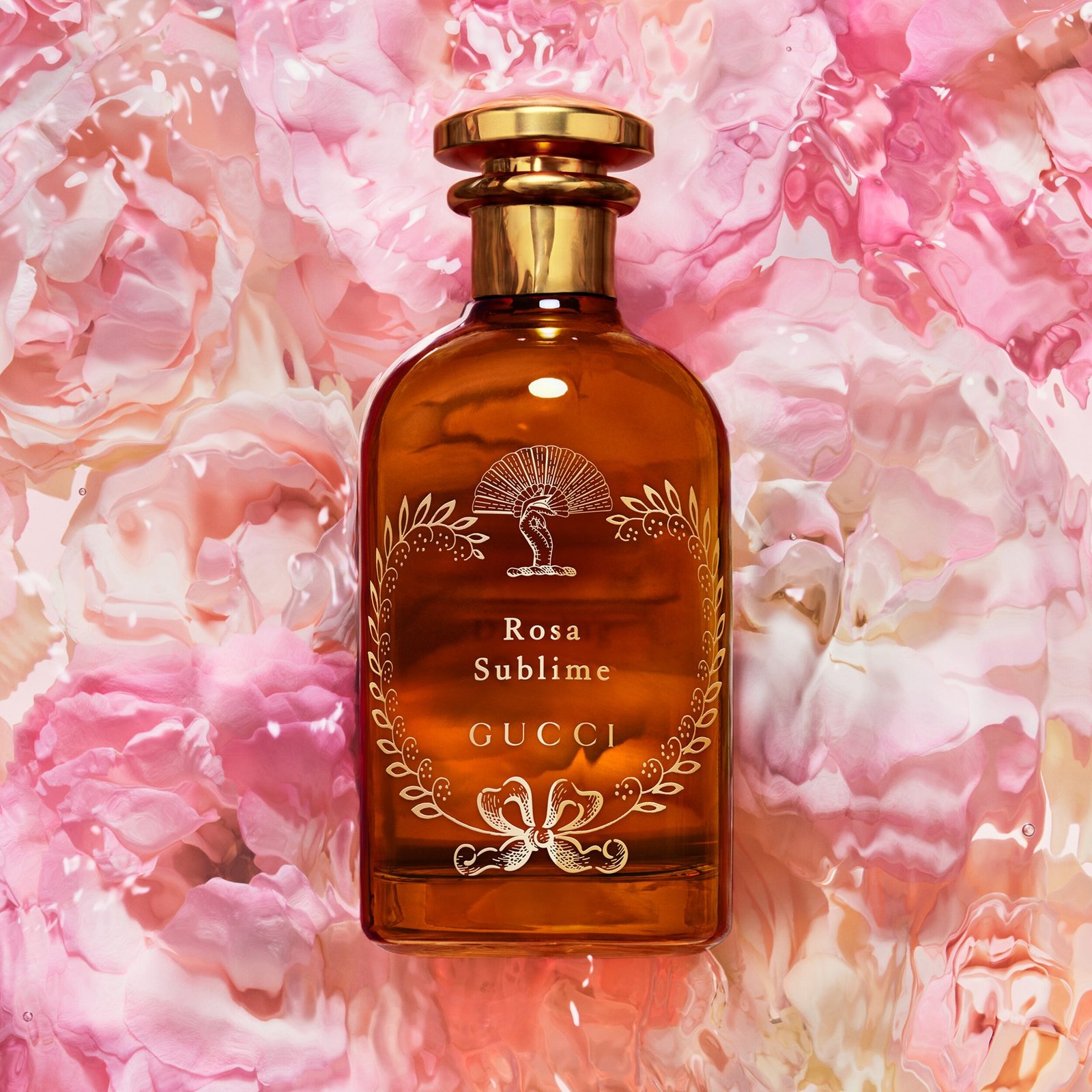 An amber Rosa Sublime bottle with a fan emblem against a rippled pink floral surface