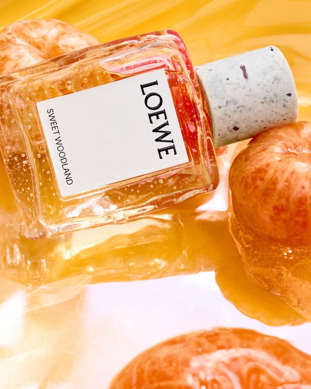 Loewe Sweet Woodland bottle with mandarin oranges in a golden-toned still life