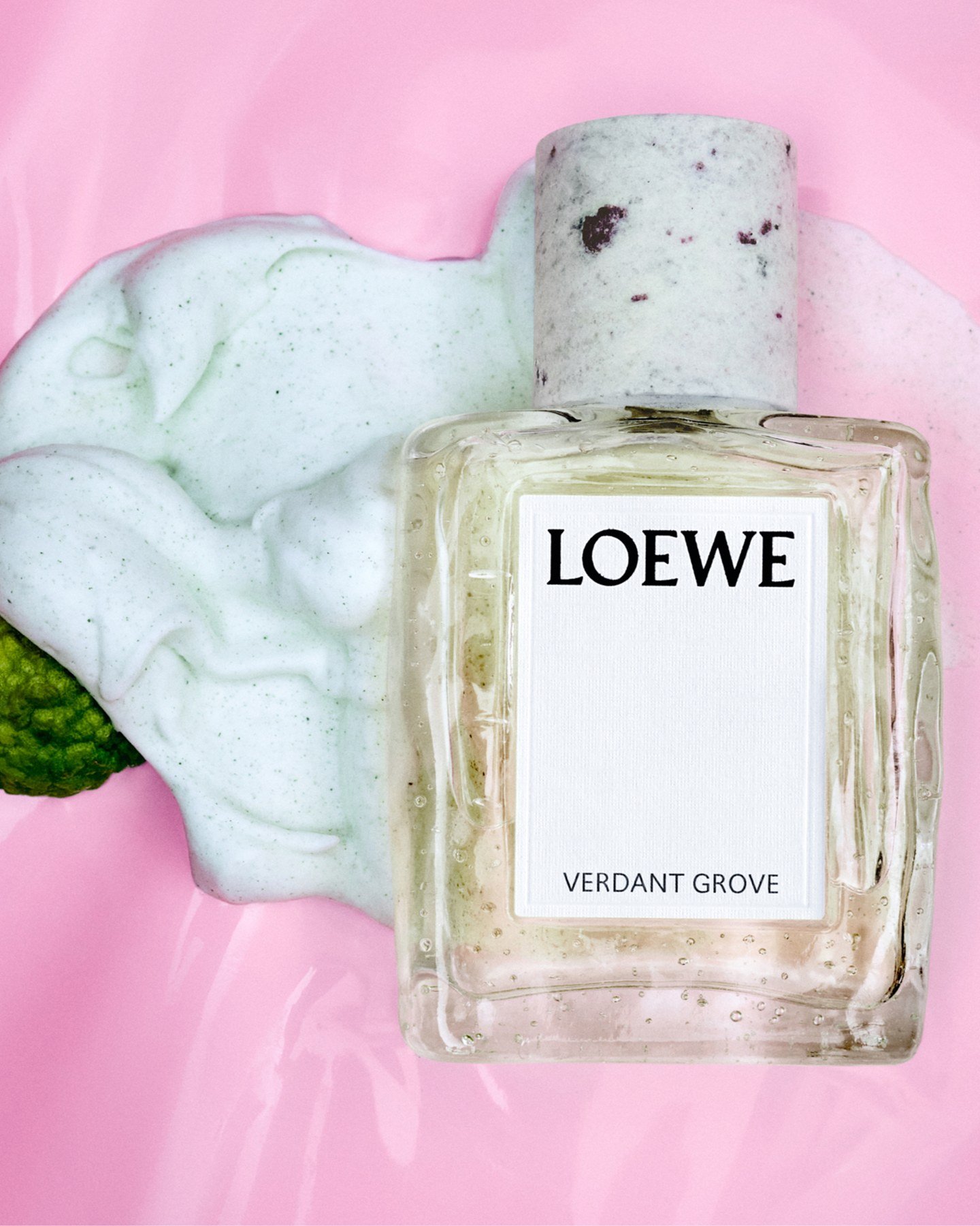 Loewe Verdant Grove bottle against a pale pink background with a marbled green-and-white form