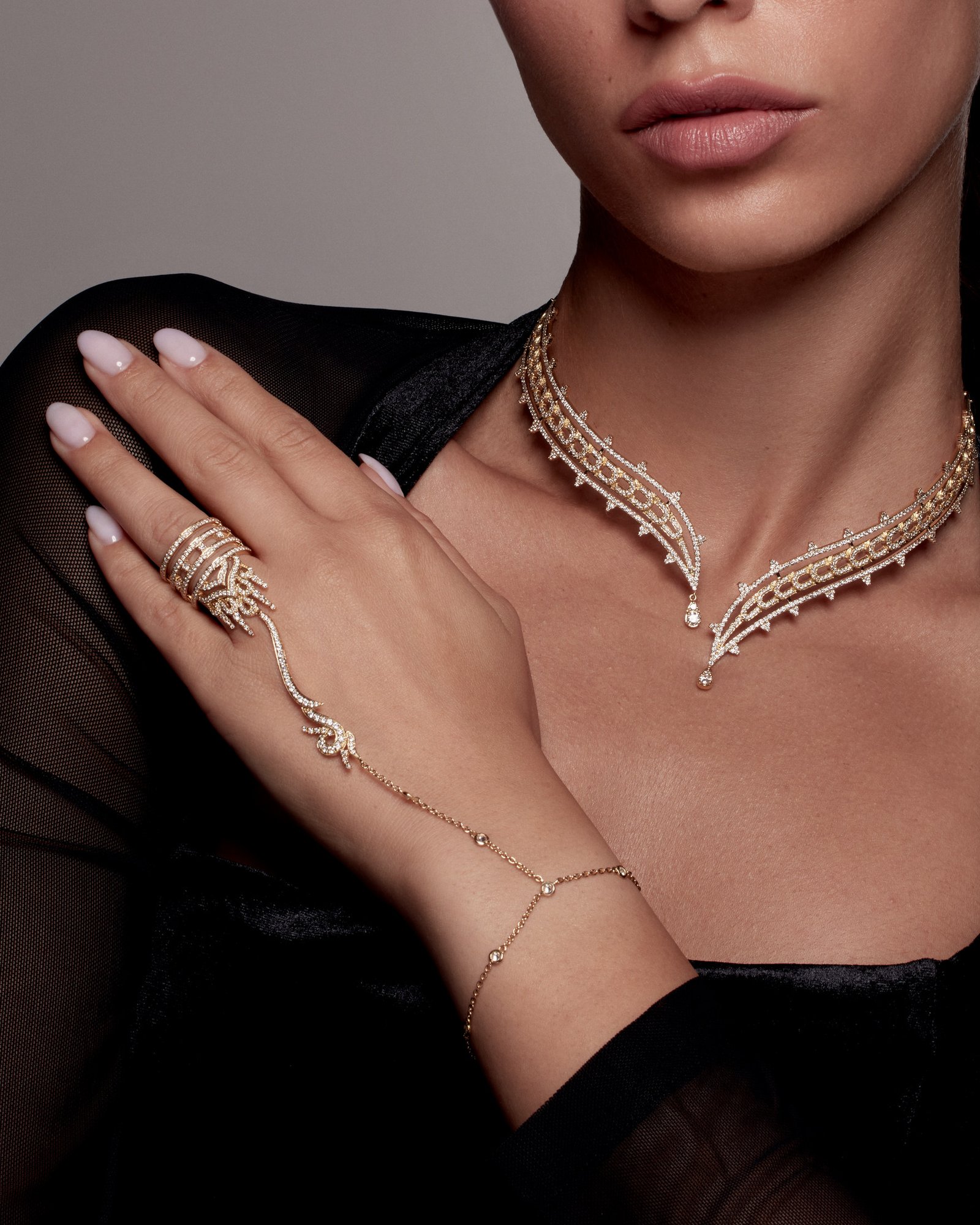 Close-up of a branching necklace and a ring connected by a fine chain to a bracelet.