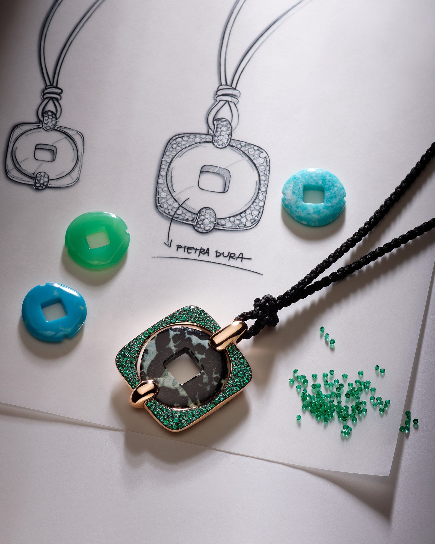 Moneta Orientale pendant beside design sketches and loose coloured stones