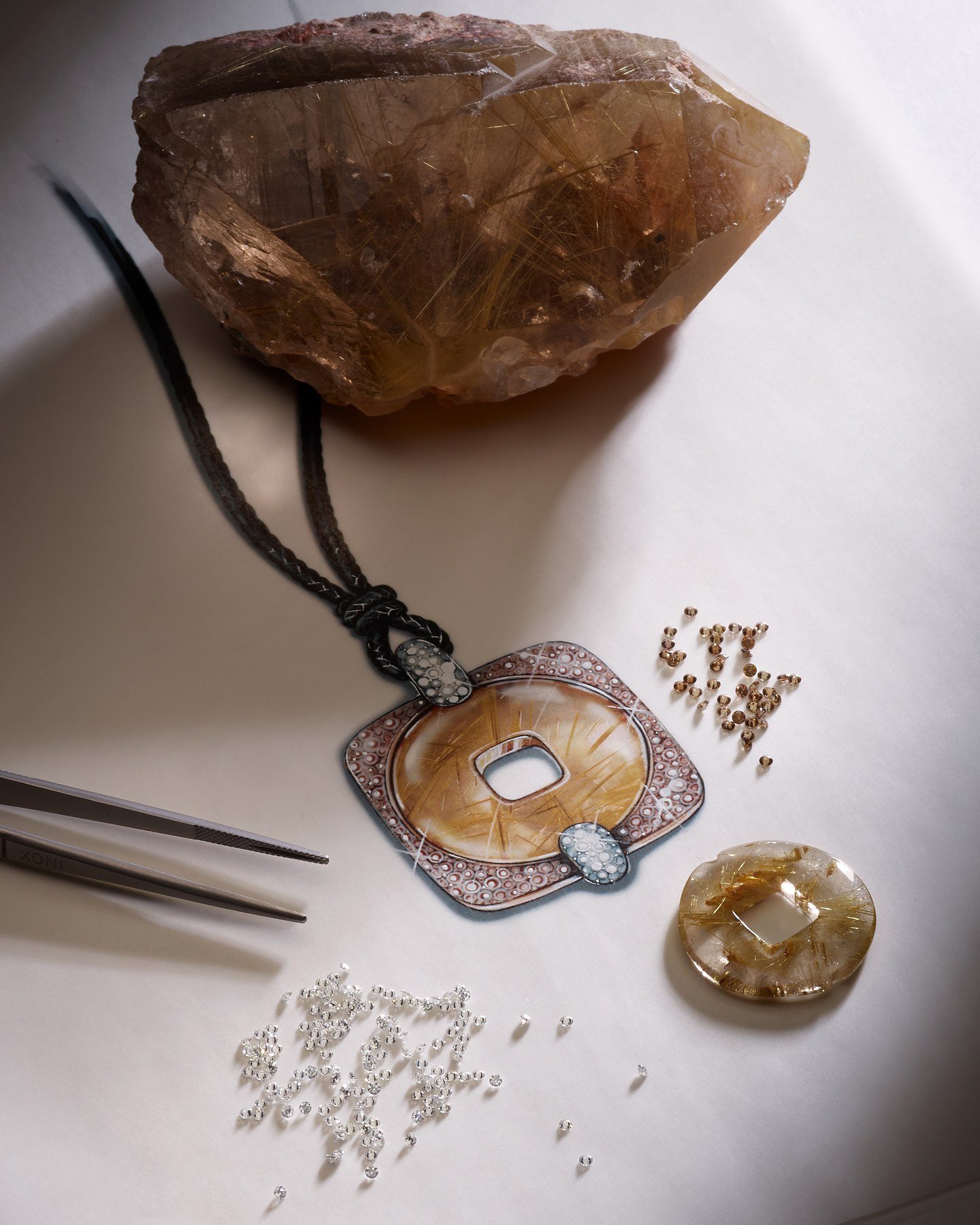 Golden-brown Moneta Orientale pendant displayed with a mineral specimen and loose stones