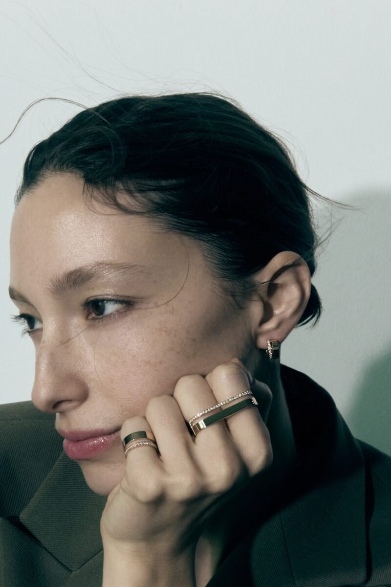 Close-up portrait of a model resting her face against a hand wearing several Repossi Berbère rings