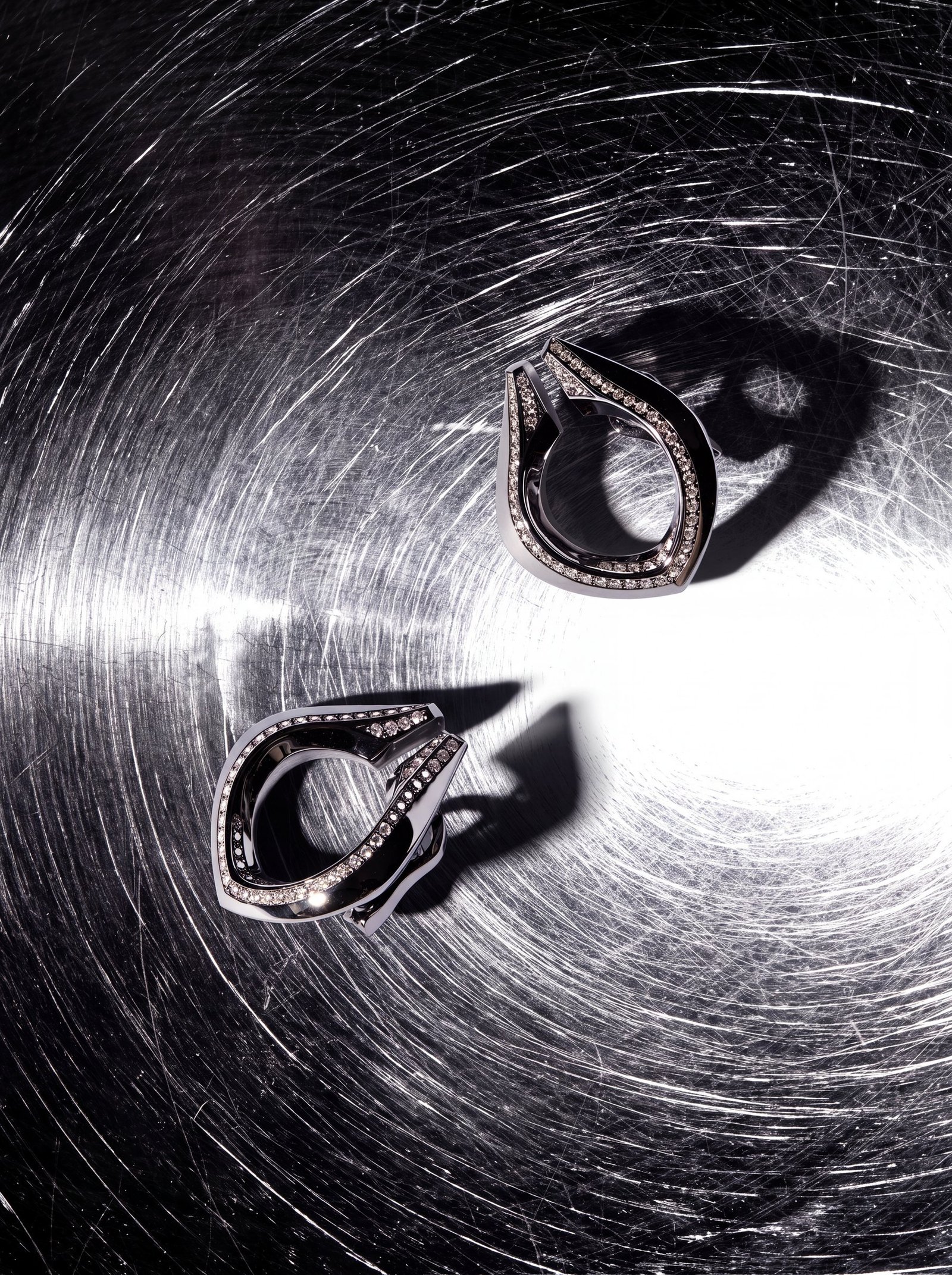 Two Repossi Limited Edition No.9 earrings on a reflective background