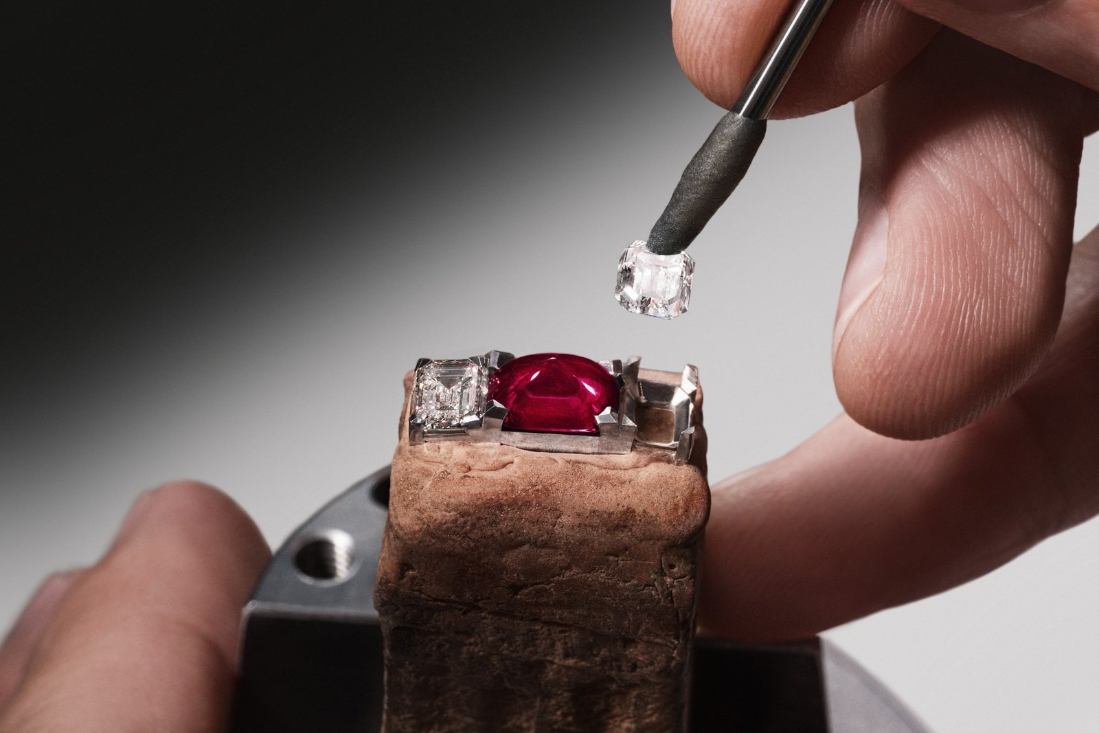 Artisan positioning a diamond beside the sugarloaf ruby of a Grand Lady Kalla jewel piece